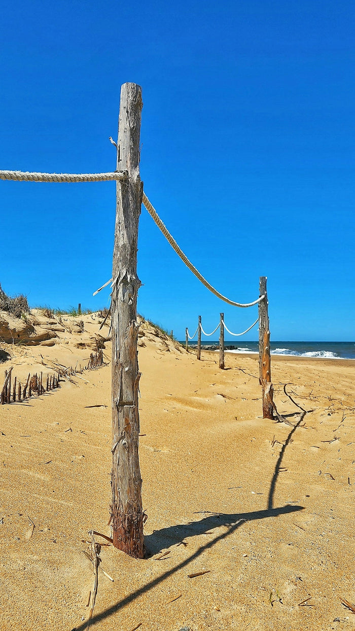 a wooden post on a sandy beach next to the ocean