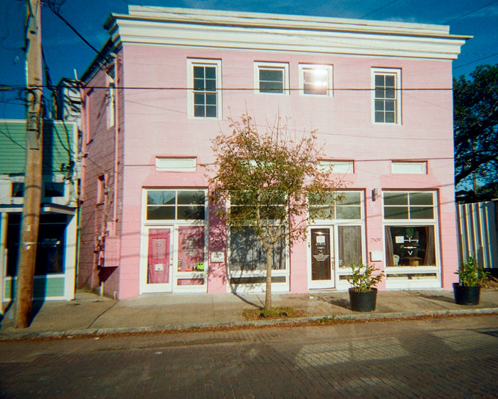 A pink building stands on a city street.